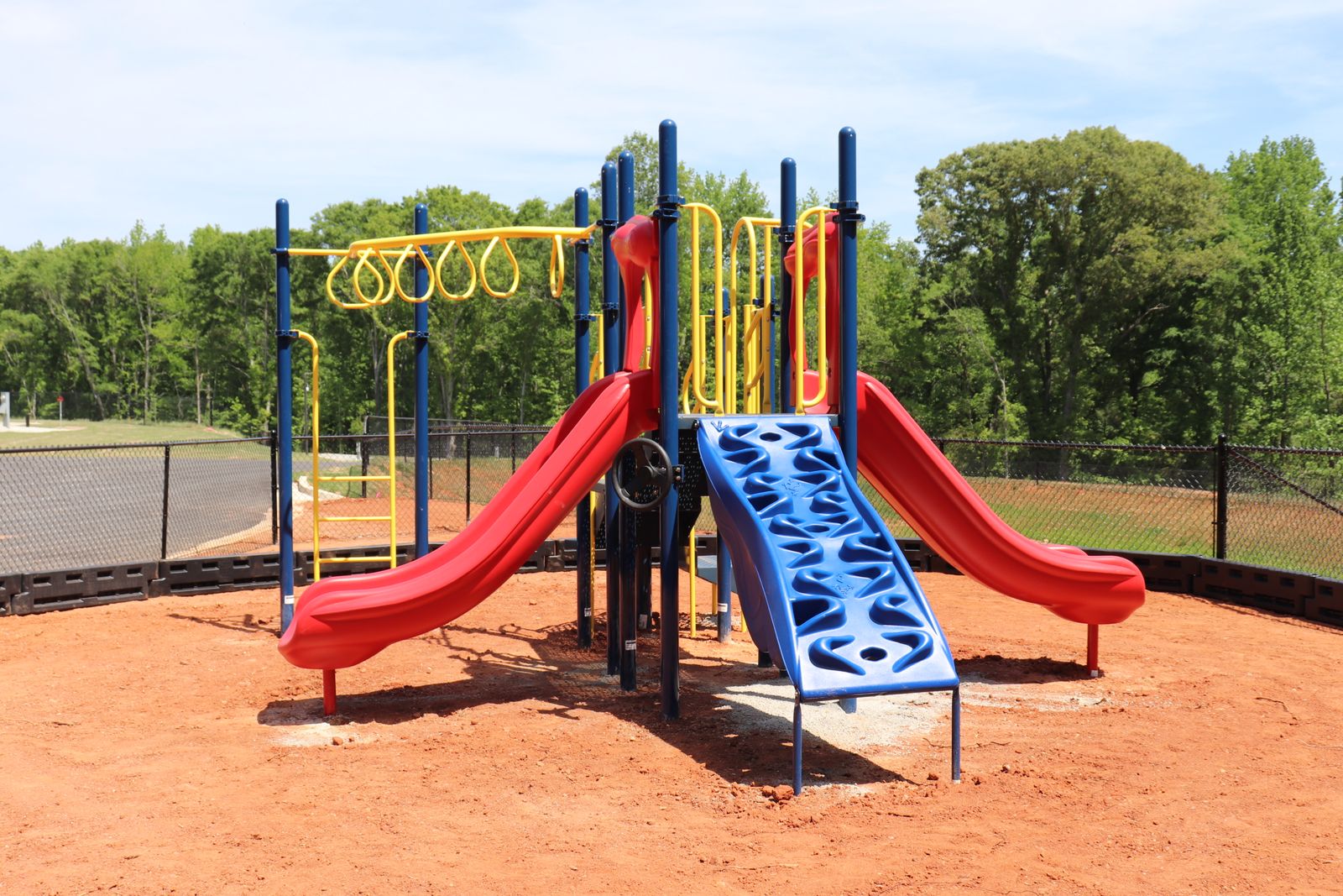 Playground with red slides, climbing wall and monkey bars